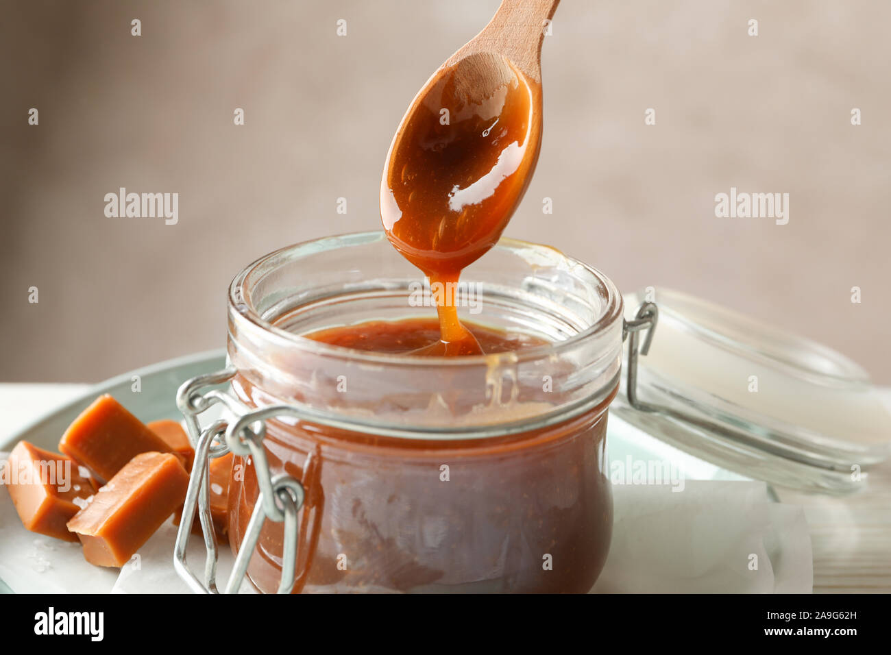 Vaso di vetro con caramello salato e caramelle su sfondo di legno, lo spazio per il testo Foto Stock