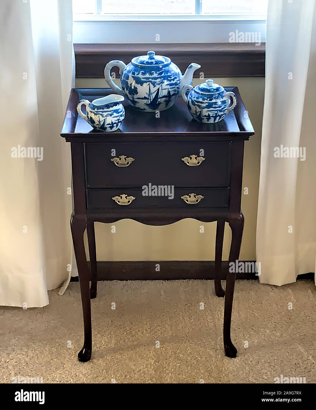 Legno di ciliegio TeaBags armadio con il blu e il salice bianco Design set da tè sulla seduta superiore al di sotto della finestra nel salotto di casa. Foto Stock