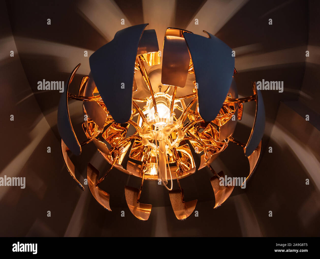 Lampada moderna scattering un morbido e caldo di luce arancione sul soffitto della camera. Foto Stock