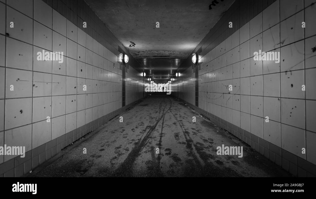 Tunnel pedonale. Un urbano sottopasso pedonale con graffiti e illuminazione soffusa che rende un clima intimidatorio ubicazione. Foto Stock