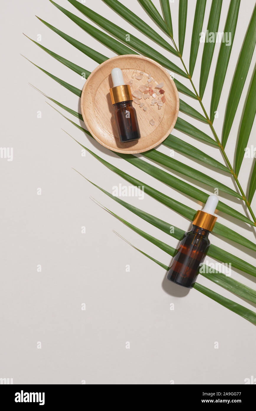 Concetto di spa con massaggi, sale in cucchiaio e bottiglie di olio essenziale con piccole lasciare Foto Stock