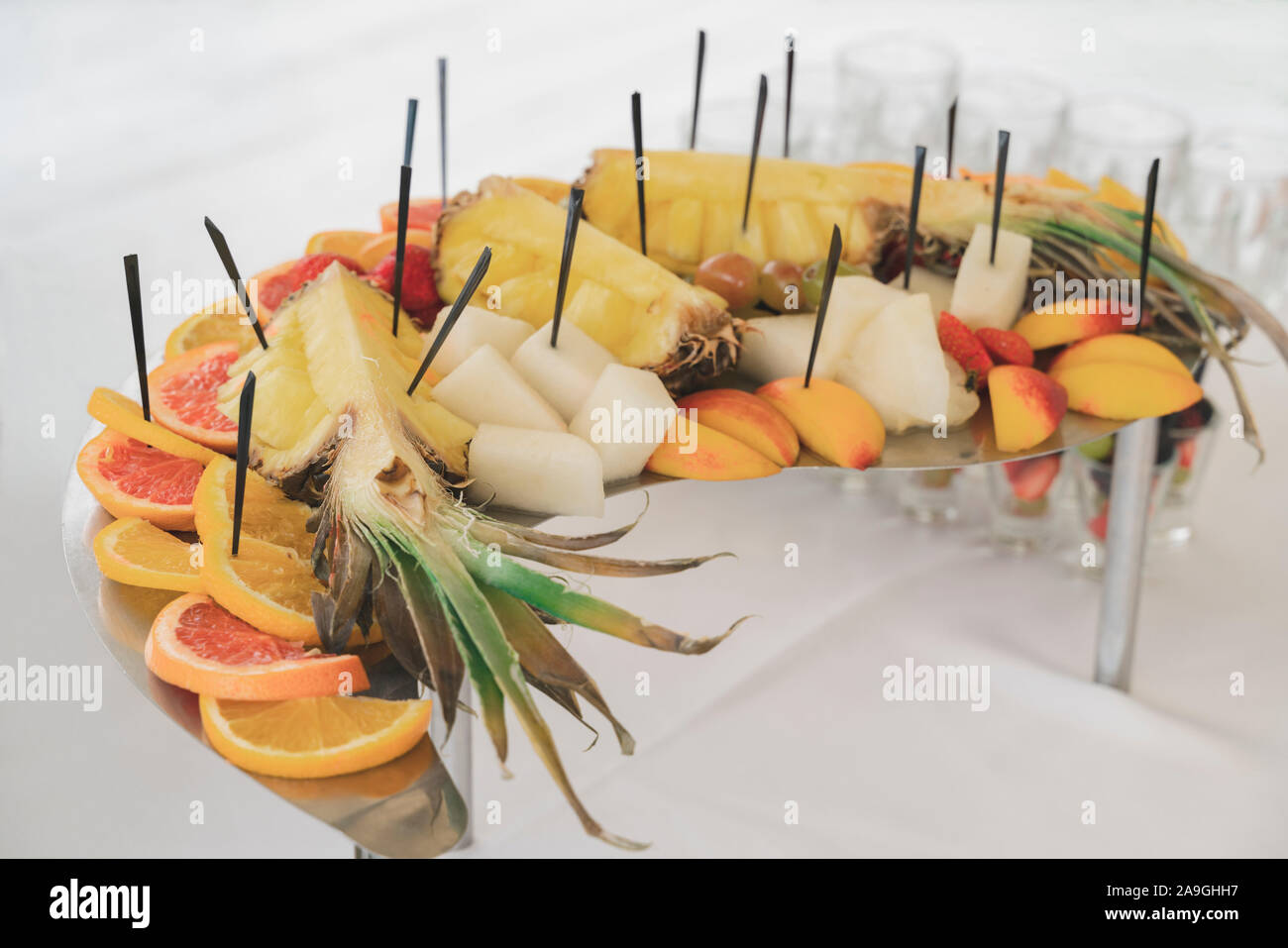 Un bel piatto di frutti, ossia: ananassi, arance, pompelmi, fragole, uva, melone e pesche. Frutta e bacche di crostini su spiedini guardare Foto Stock
