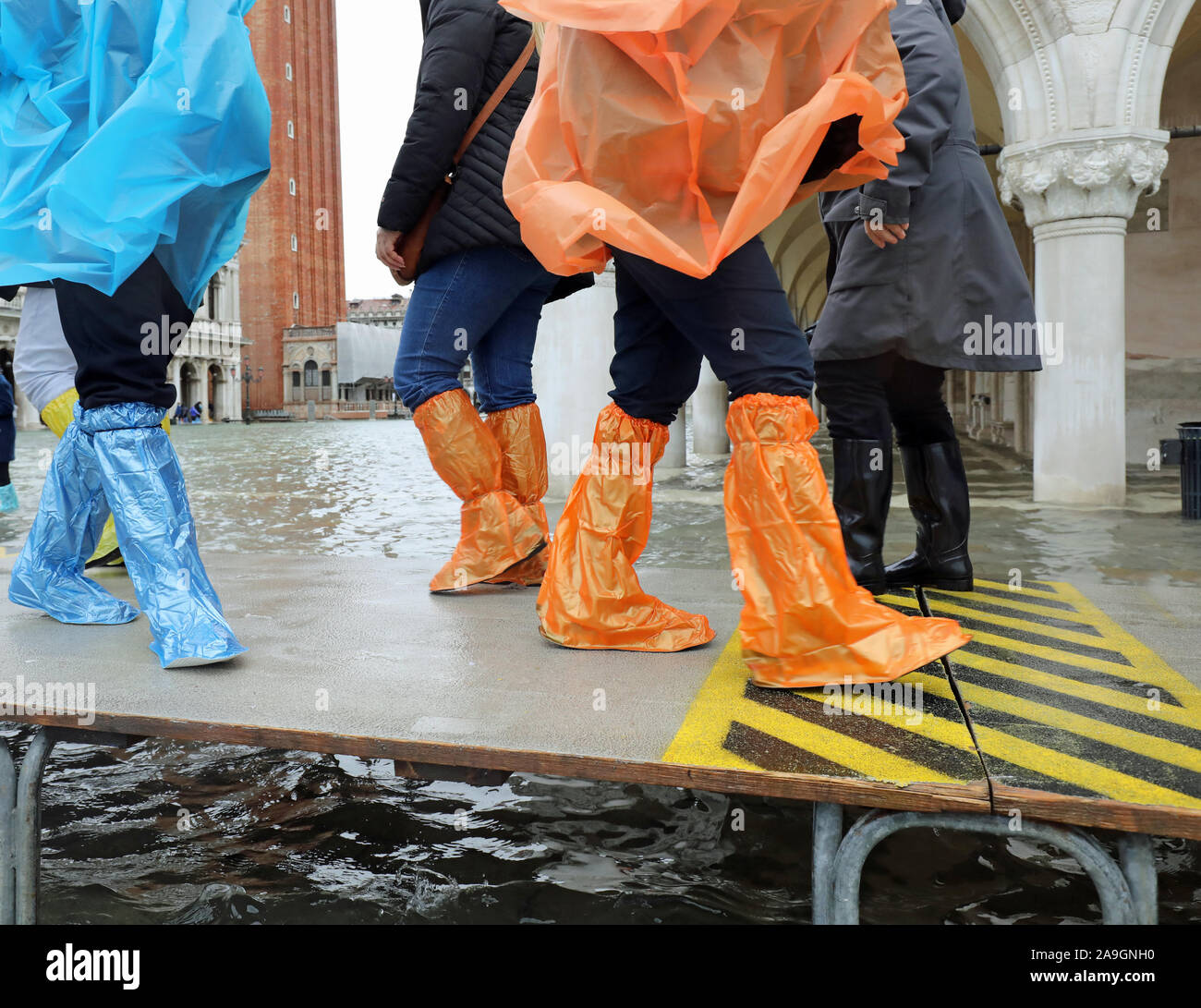 Il movimento di persone con pioggia di cappotti e gambali in plastica sulla  passerella a Venezia in Italia durante l'alluvione Foto stock - Alamy