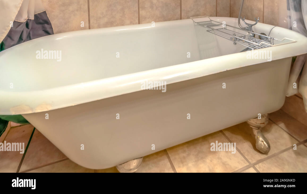 Panorama da vicino alla vasca da bagno e doccia all'interno di una sala da bagno con piastrelle a parete e a pavimento Foto Stock
