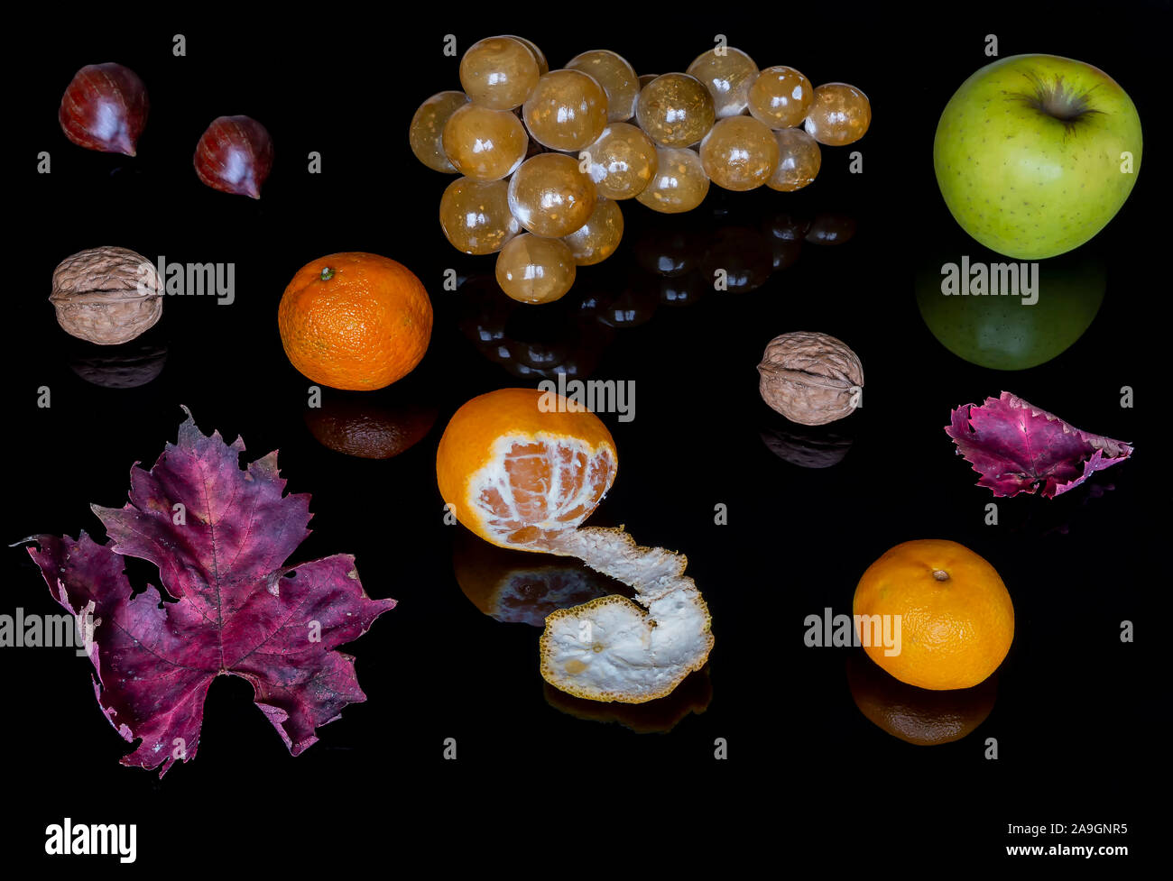 Bella composizione di frutti autunnali e foglie su un lucido sfondo nero con la riflessione Foto Stock
