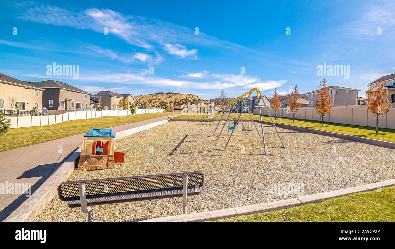 Panorama banco vuoto che si affaccia su un piccolo parco giochi per bambini Foto Stock