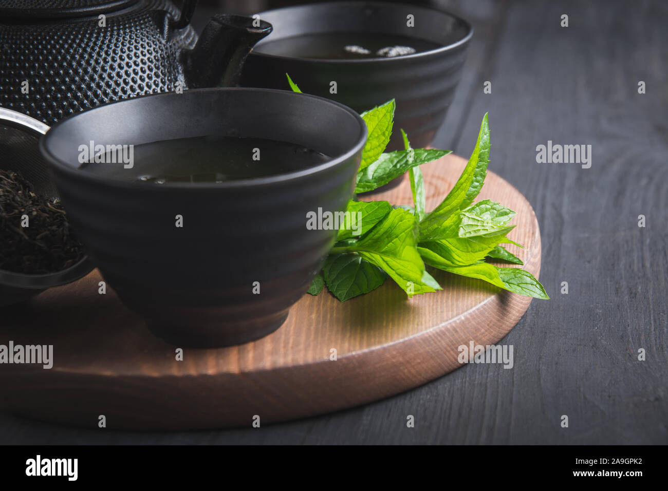 Il tè caldo con la menta in tazza nera su sfondo scuro. Il tè cinese. Asian ancora in vita. Close up. Foto Stock