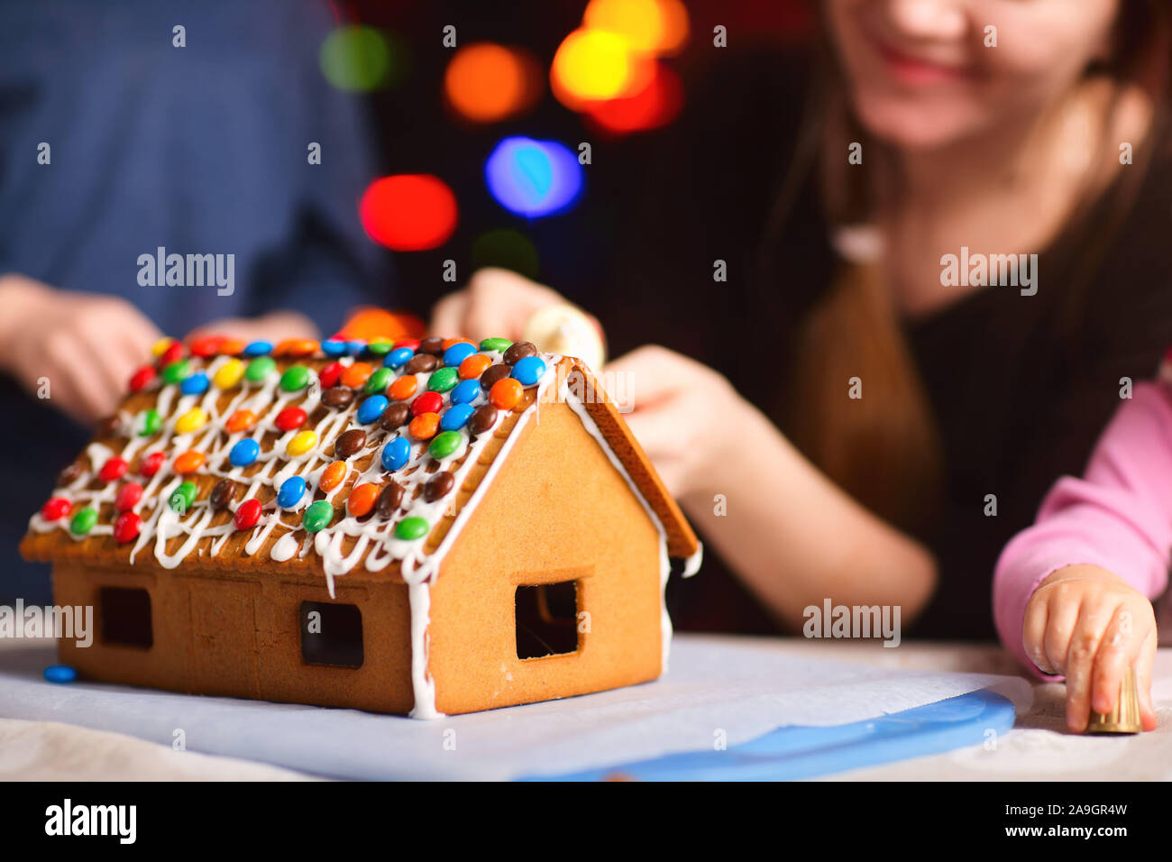 Mutter und 2 Kinder bauen Lebkuchenhaus zusammen Foto Stock