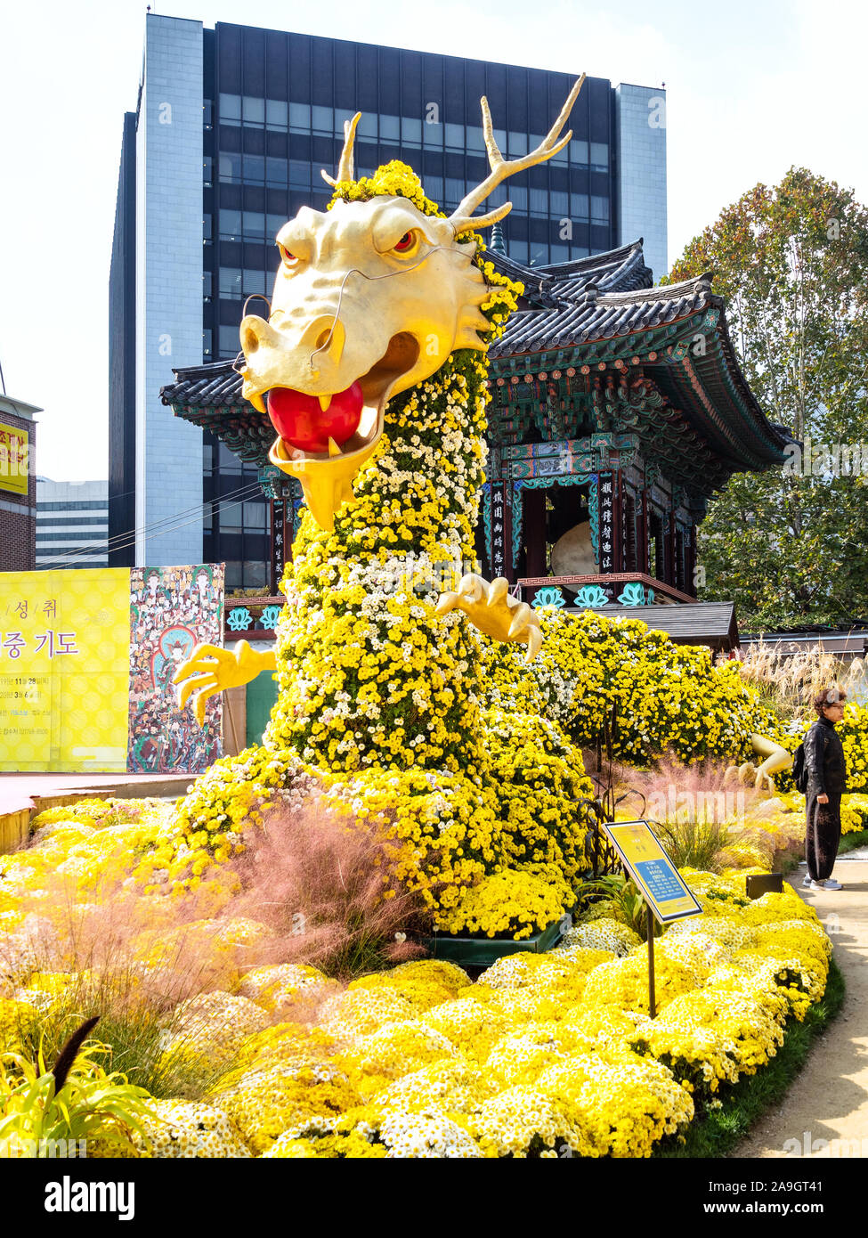 SEOUL, Corea del Sud - 30 ottobre 2019: turistico vicino alla statua del drago su aiuola di fiori nel giardino ornamentale di Tempio Jogyesa a Seoul Città. Jogyesa è principale t Foto Stock