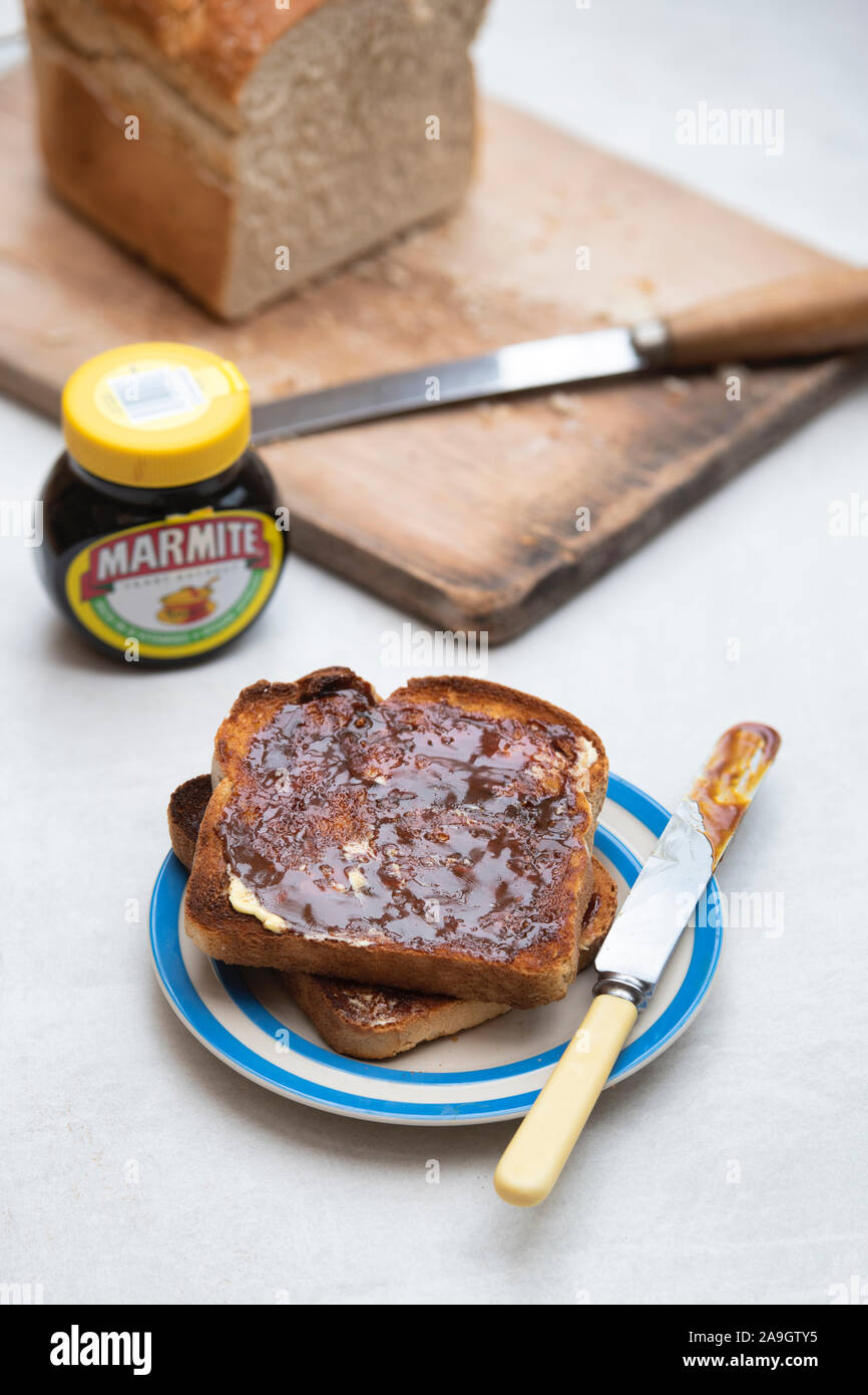 Marmite su toast sulla piastra vicino ad una pagnotta di pane bianco e un vaso di marmite Foto Stock