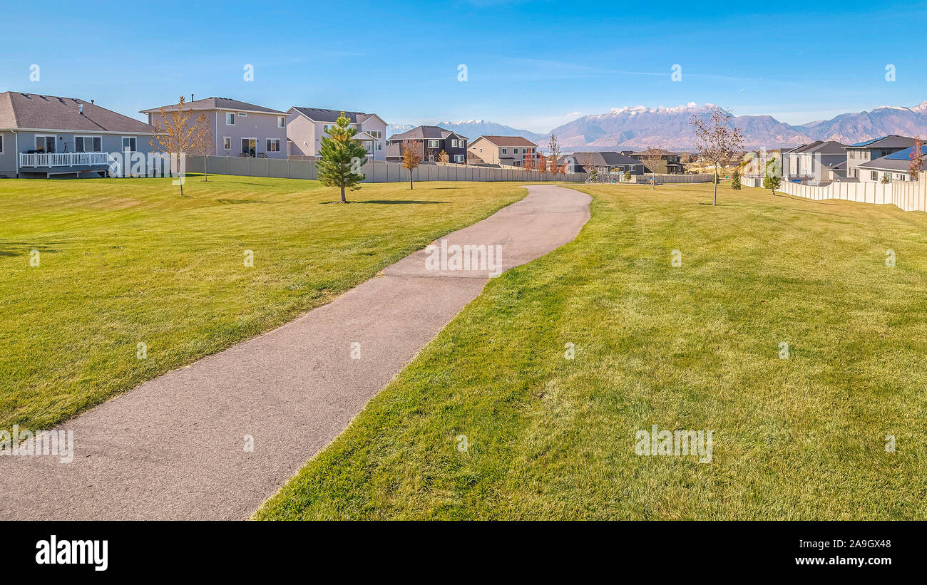 Panorama sentiero pavimentato attraverso un parco residenziale vicino al tramonto Foto Stock