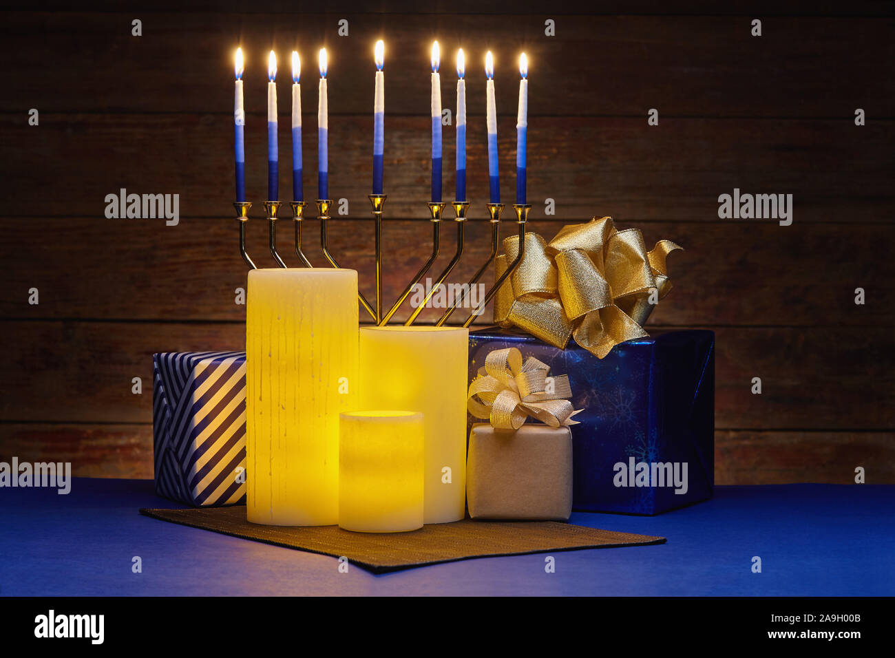 Hanukkah ancora in vita di incandescente giallo candele elettrica, lit menorah e avvolti doni Foto Stock