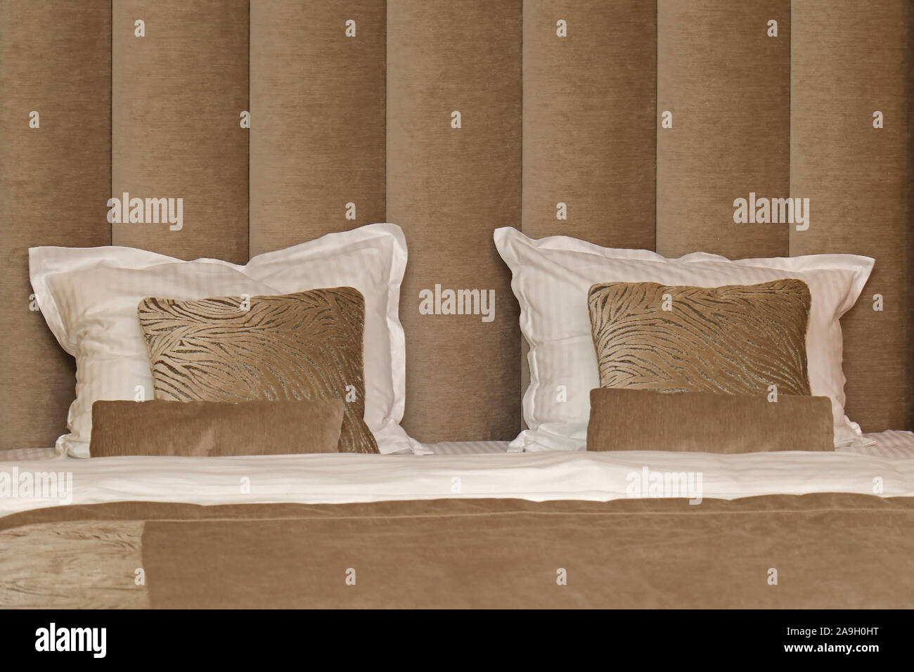 Comodi cuscini decorativi sulla parte superiore del letto moderno con testata in pelle resto Foto Stock