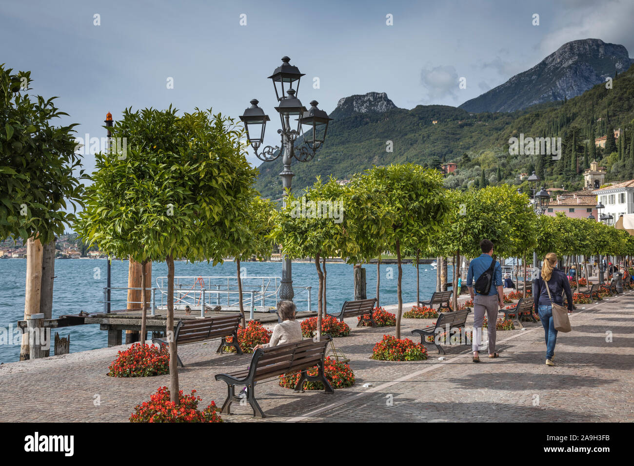 I turisti passeggiare lungo la passeggiata lungo il lago del grazioso borgo di Gargnano sul Lago di Garda, Italia Foto Stock