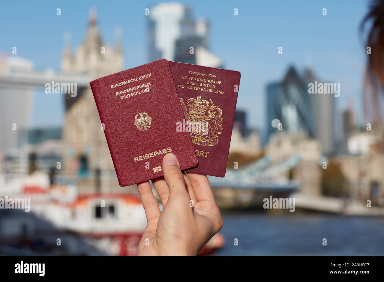 Mano che tiene il passaporto britannico insieme con altri passaporto UE contro il simbolo di Londra. Il viaggio dopo Brexit. Foto Stock