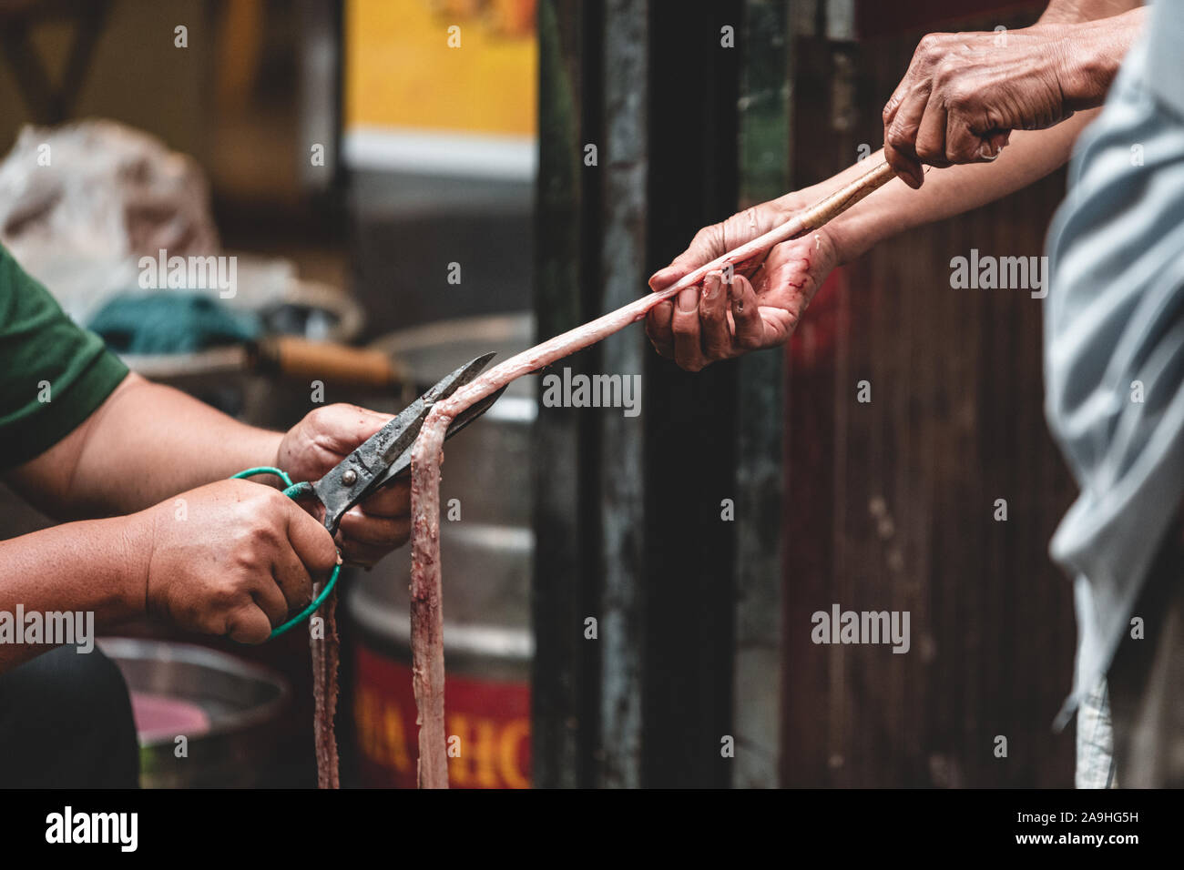 Due uomini asiatici in un vicolo tagliata aperta nell'intestino o un'anguilla a prepararlo per un mercato o un cibo di strada Foto Stock