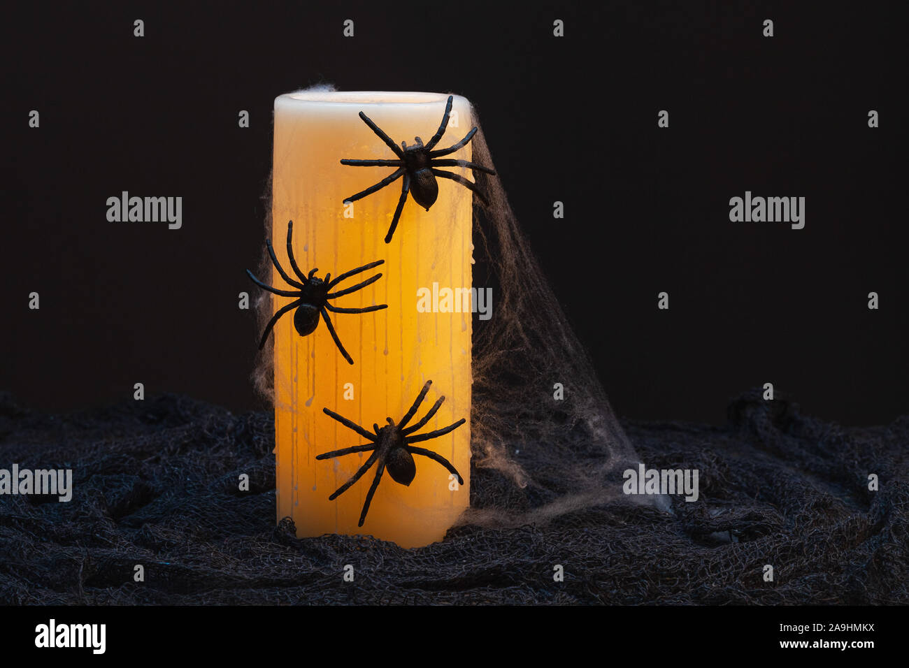 Halloween holiday ancora la vita di un giallo elettrico candela di cera ricoperta con ragni Foto Stock