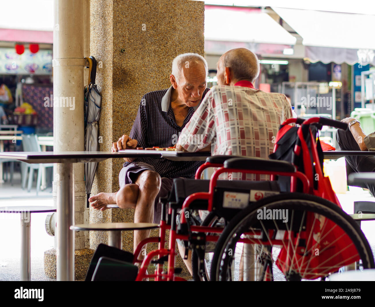 SINGAPORE, 12 apr 2019 - Due vecchi pensionati maschio / pensionati godere di un gioco di scacchi cinesi in un Hawker centro. Singapore ha un rapido invecchiamento della popolazione Foto Stock