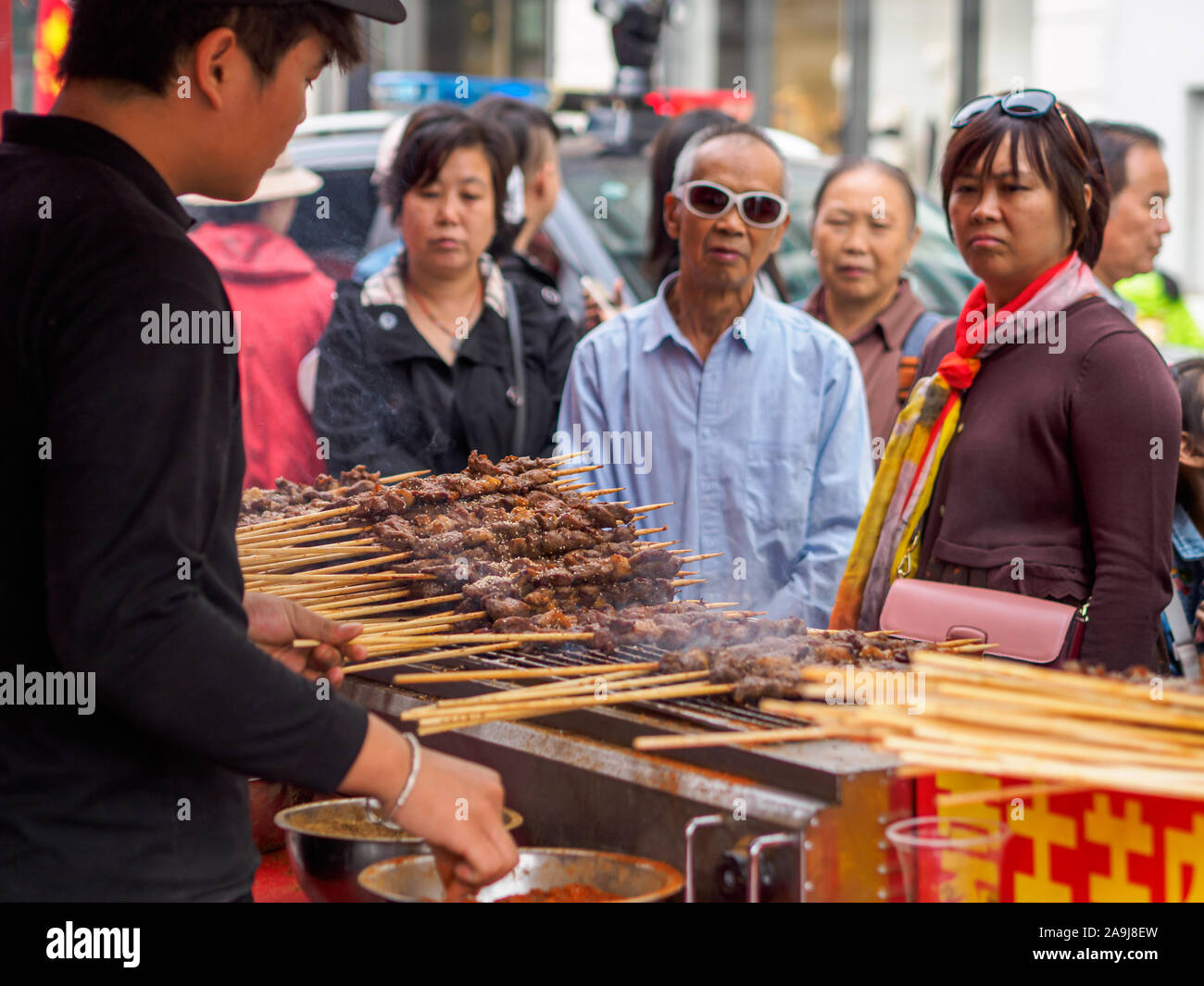 TIANJIN, Cina - 6 ott 2019 - aspettare i clienti per i loro ordini di stile dello Xinjiang grigliate spiedini di agnello in una strada di stallo alimentare. Spiedini di agnello sono un popul Foto Stock