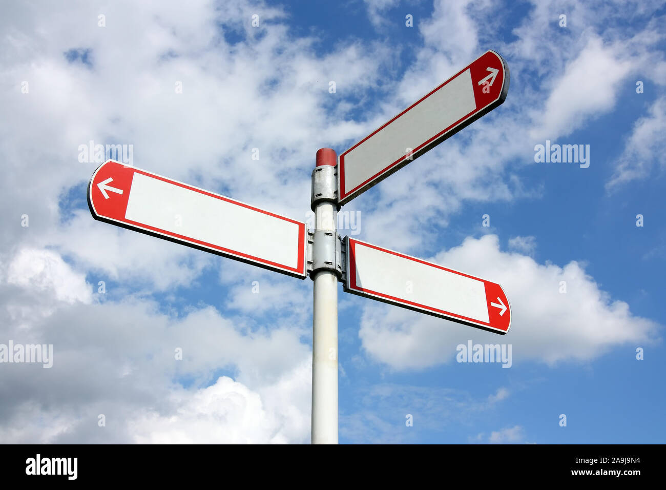 Vuoto direzionale tre cartelli stradali in bianco e rosso contro il cielo blu con nuvole Foto Stock