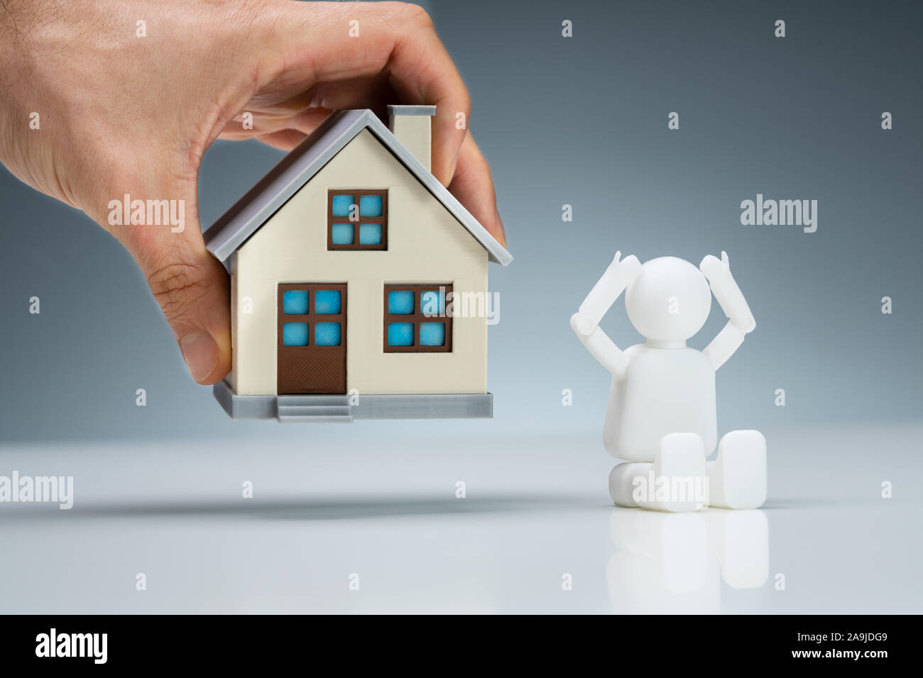 Close-up di mano di una persona tenendo lontano il modello della casa vicino ha sottolineato la figura umana. Foto Stock