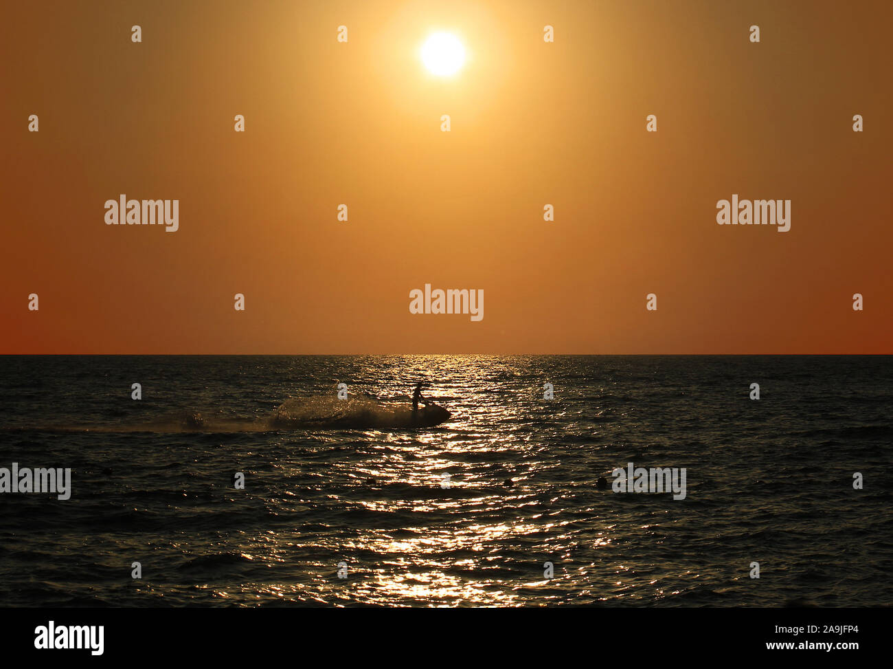 Un getto sciatore cavalcando attraverso il tramonto nel mare Mediterraneo. Foto Stock