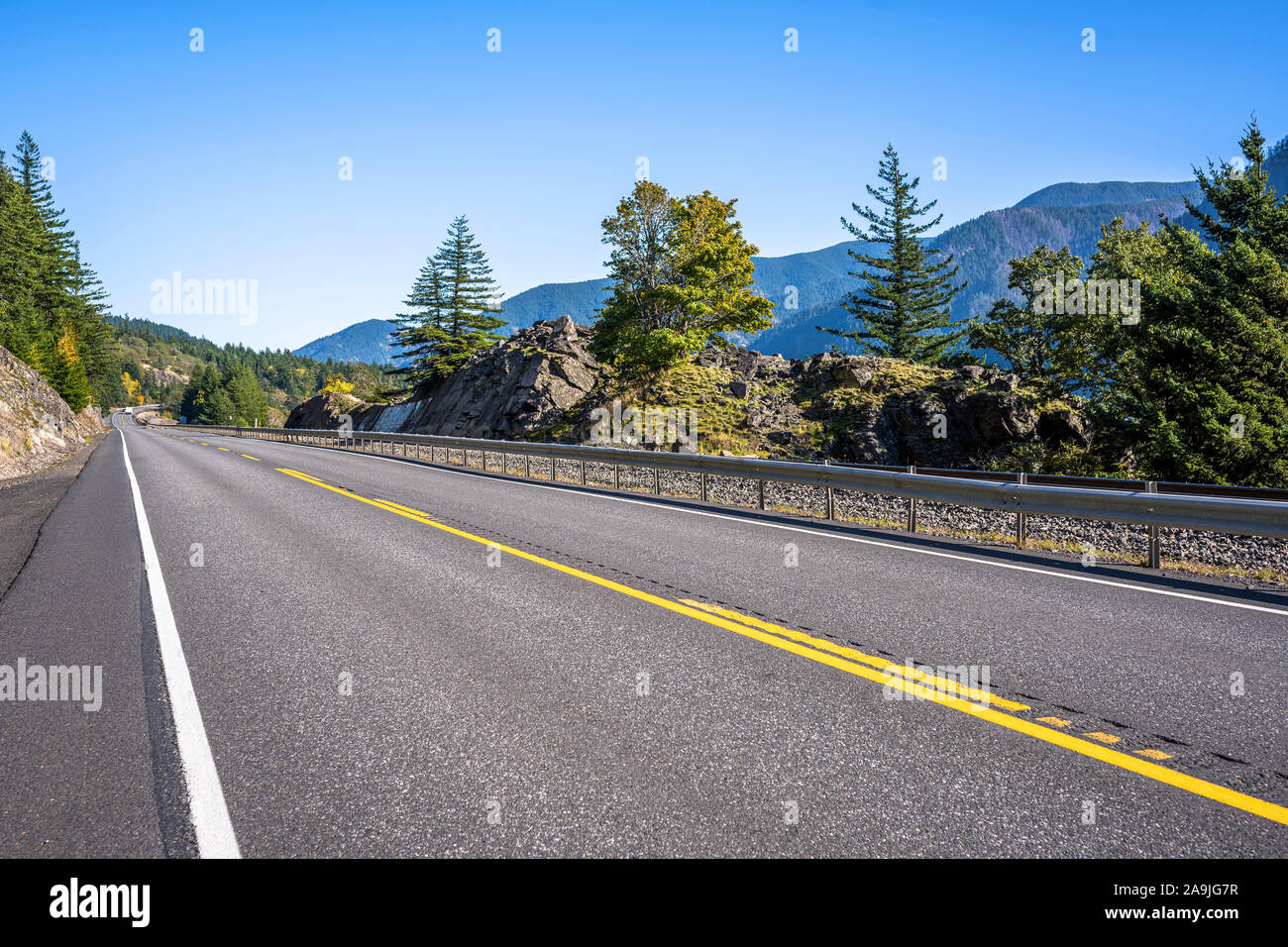 Un incantevole paesaggio che attrae i turisti con una strada rettilinea con cartello stradale attorno ad una roccia su un lato e un abisso sull'altro lato in t Foto Stock