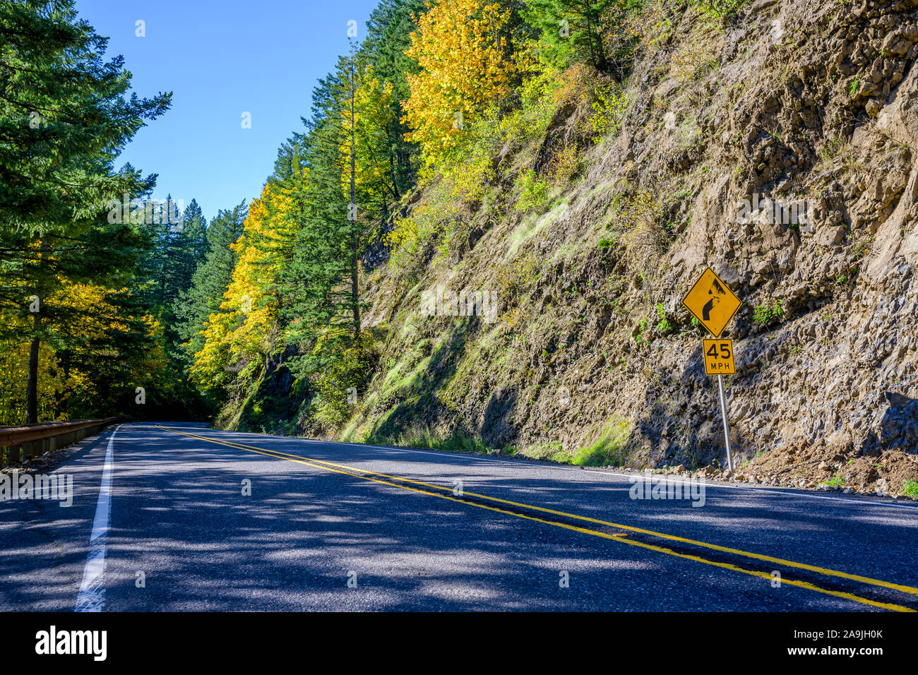 Un incantevole paesaggio che attrae i turisti con una tortuosa strada con cartello stradale attorno ad una roccia su un lato e un abisso sull'altro lato in th Foto Stock