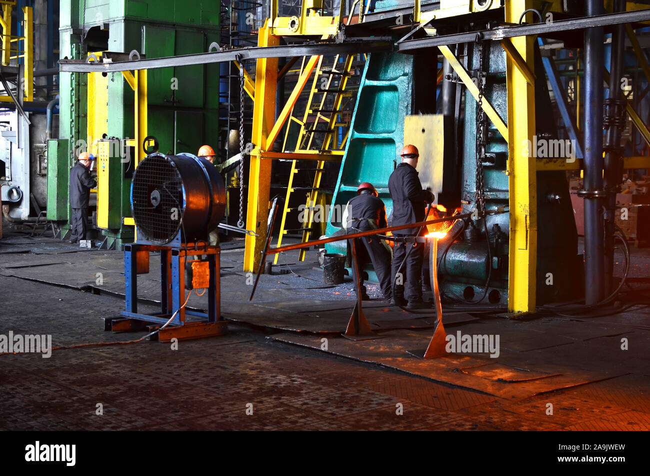 Processi di fabbro red ferro caldo sotto un enorme premere. Fucinato metallico, stampaggio sotto un martello forge in officina di forge foctory. Blacksmithing, meta Foto Stock