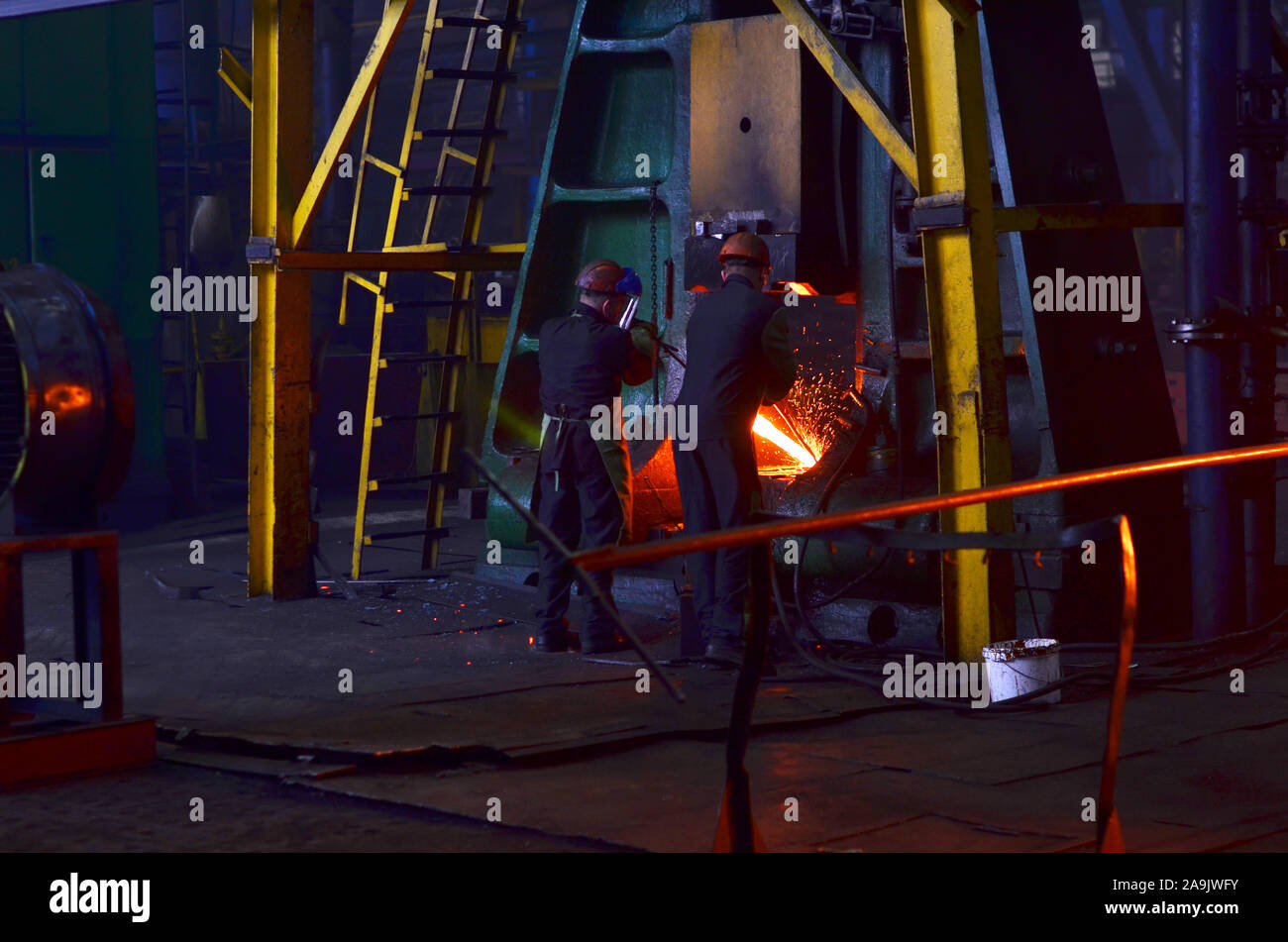 Processi di fabbro red ferro caldo sotto un enorme premere. Fucinato metallico, stampaggio sotto un martello forge in officina di forge foctory. Blacksmithing, meta Foto Stock