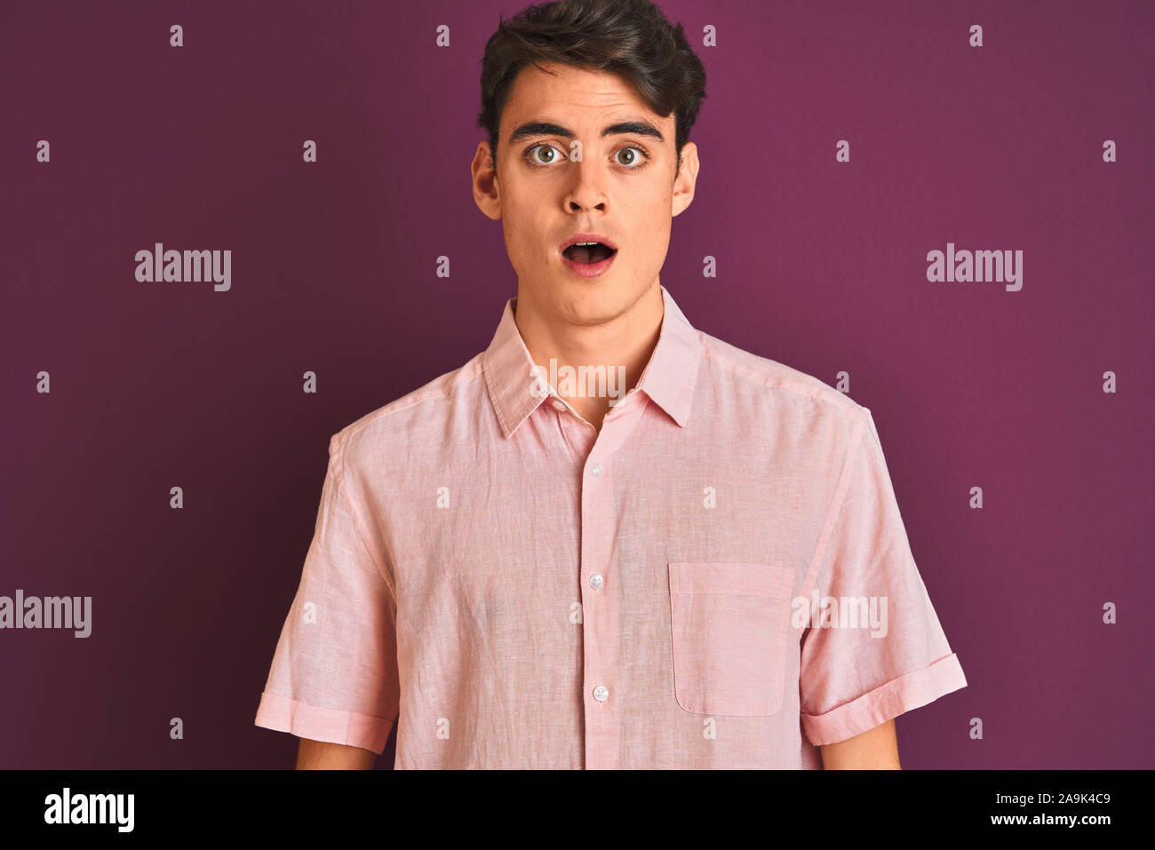 Adolescente ragazzo indossa maglia rosa in piedi su viola sfondo isolato  paura e scioccato con sorpresa di espressione, paura ed entusiasti di  faccia Foto stock - Alamy