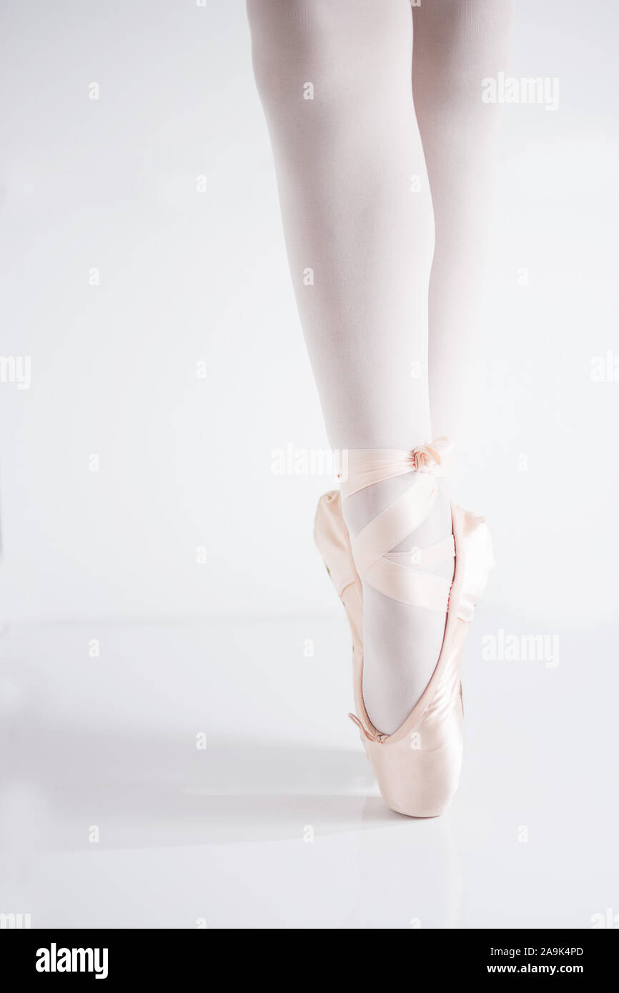 Dettaglio delle gambe e dei piedi con raso rosa pointe le scarpe di una ballerina classica in punta di piedi Foto Stock