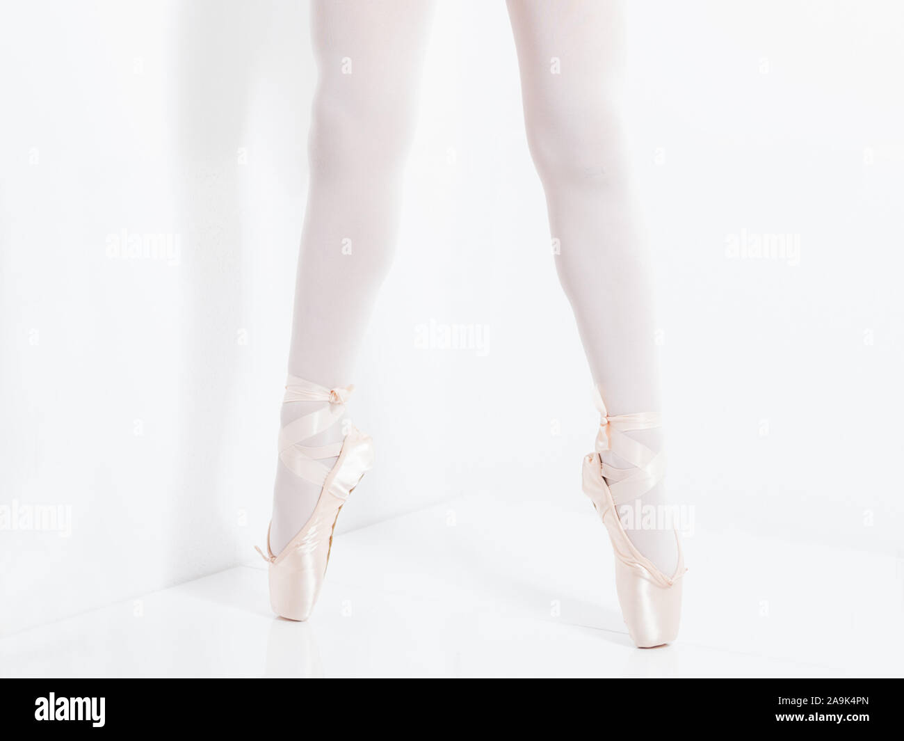 Dettaglio delle gambe e dei piedi con raso rosa pointe le scarpe di una ballerina classica in punta di piedi Foto Stock