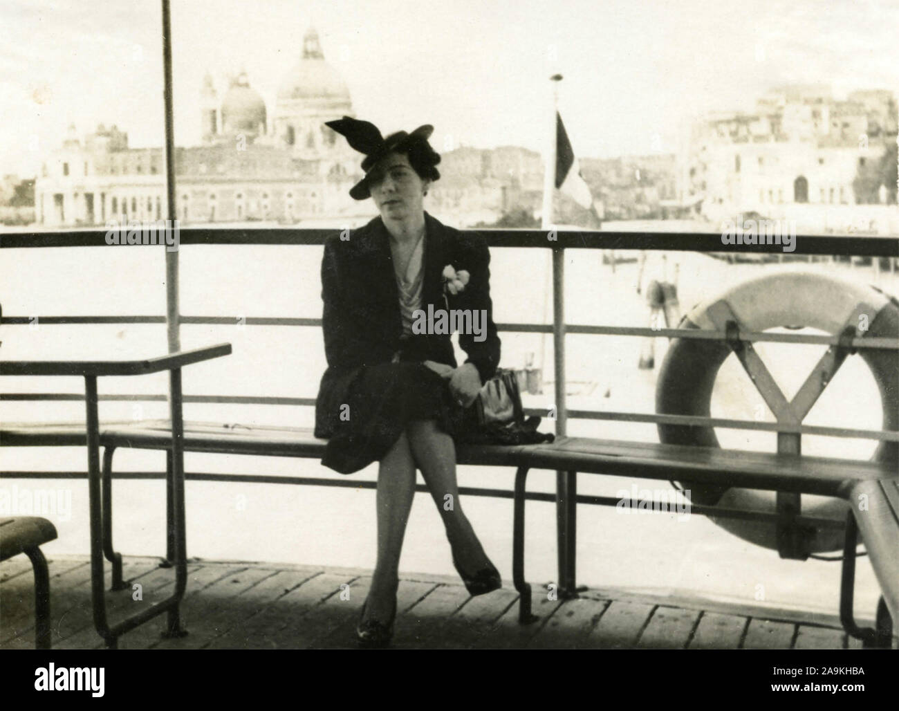 Una donna con una piuma nel suo cappuccio in un vaporetto a Venezia, Italia Foto Stock