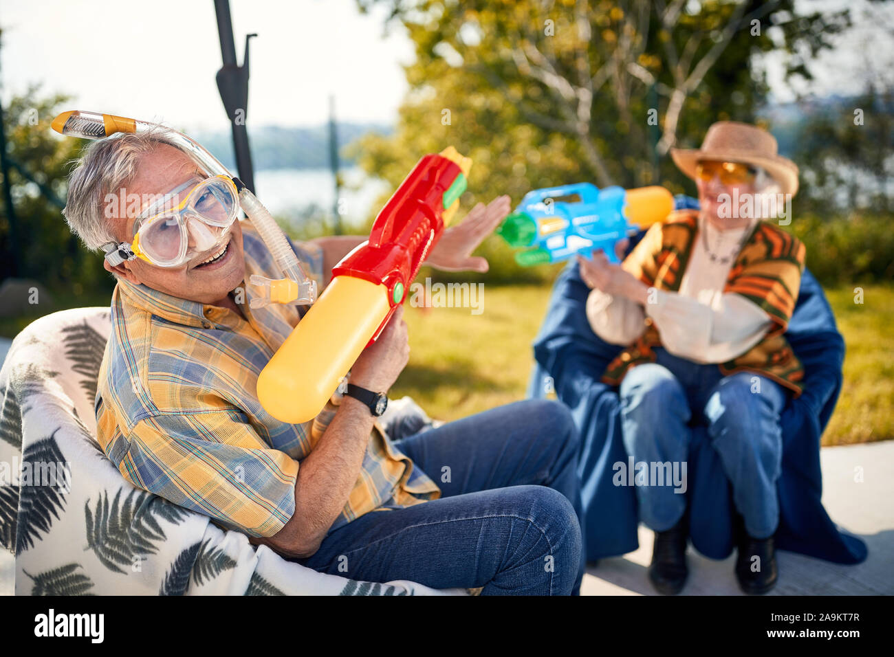 Divertente vacanza.sorridente coppia Senior giocando con la pistola ad acqua Foto Stock