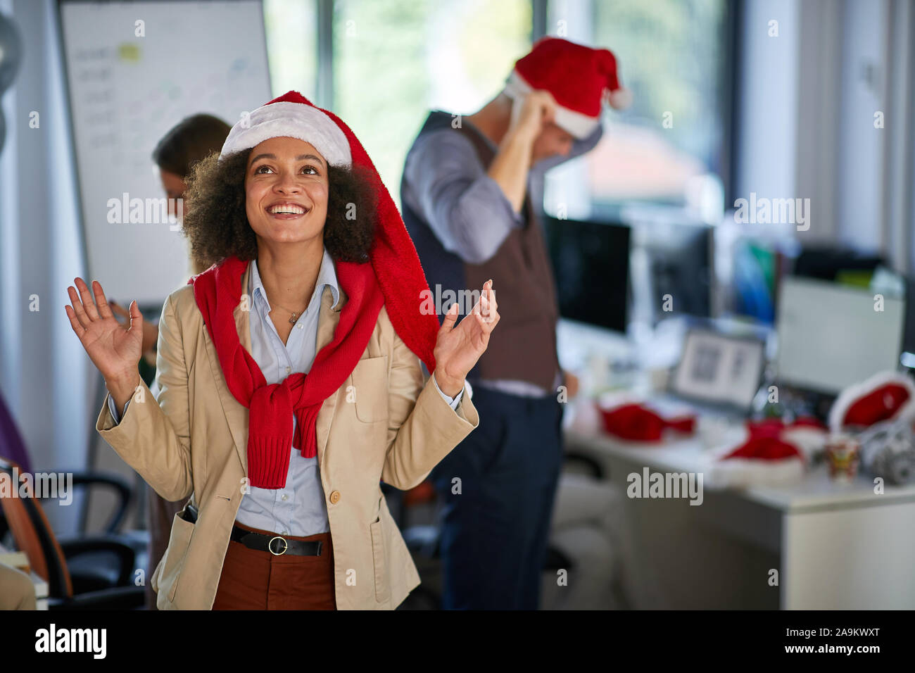 Natale in ufficio.Donna sorridente in santa hat in ufficio sulla società. Foto Stock