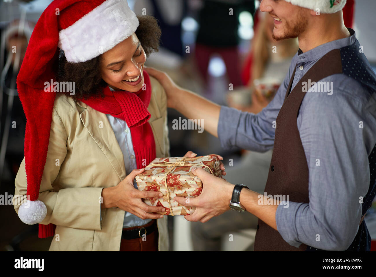 Festa di Natale in compagnia.popolo sorridente in santa hat Natale dando presen Foto Stock