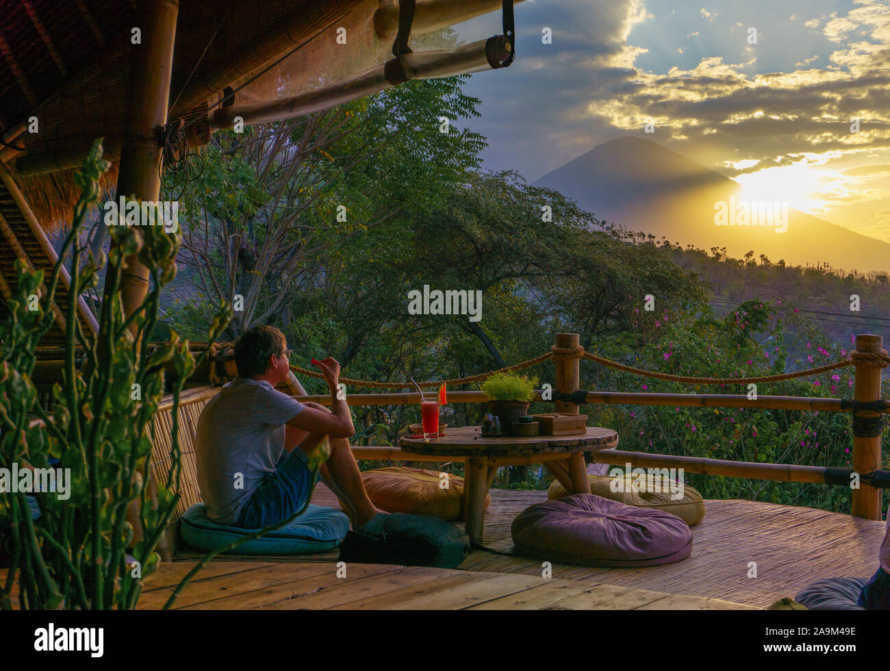 Una persona godendo la vista del Monte Agung dalla terrazza del ristorante a Amed, Bali. Gunung Agung è un vulcano attivo. Foto Stock
