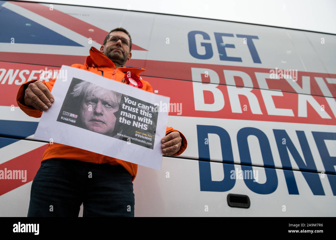 Mansfield, Nottinghamshire, Inghilterra, Regno Unito. Il 16 novembre 2019. Andy Abrahams il lavoro eletto sindaco Executive per Mansfield protestando circa i tagli in N.H.S. tenendo un poster di fronte Boris Johnson battaglia Bus. Credito: Alan Beastall/Alamy Live News Foto Stock