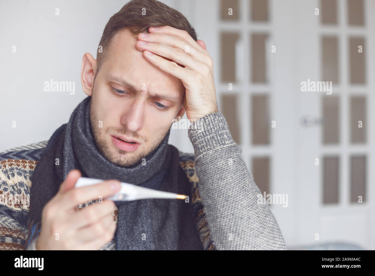 Uomo malato imparare circa la sua alta temperatura in casa nel salotto. Foto Stock