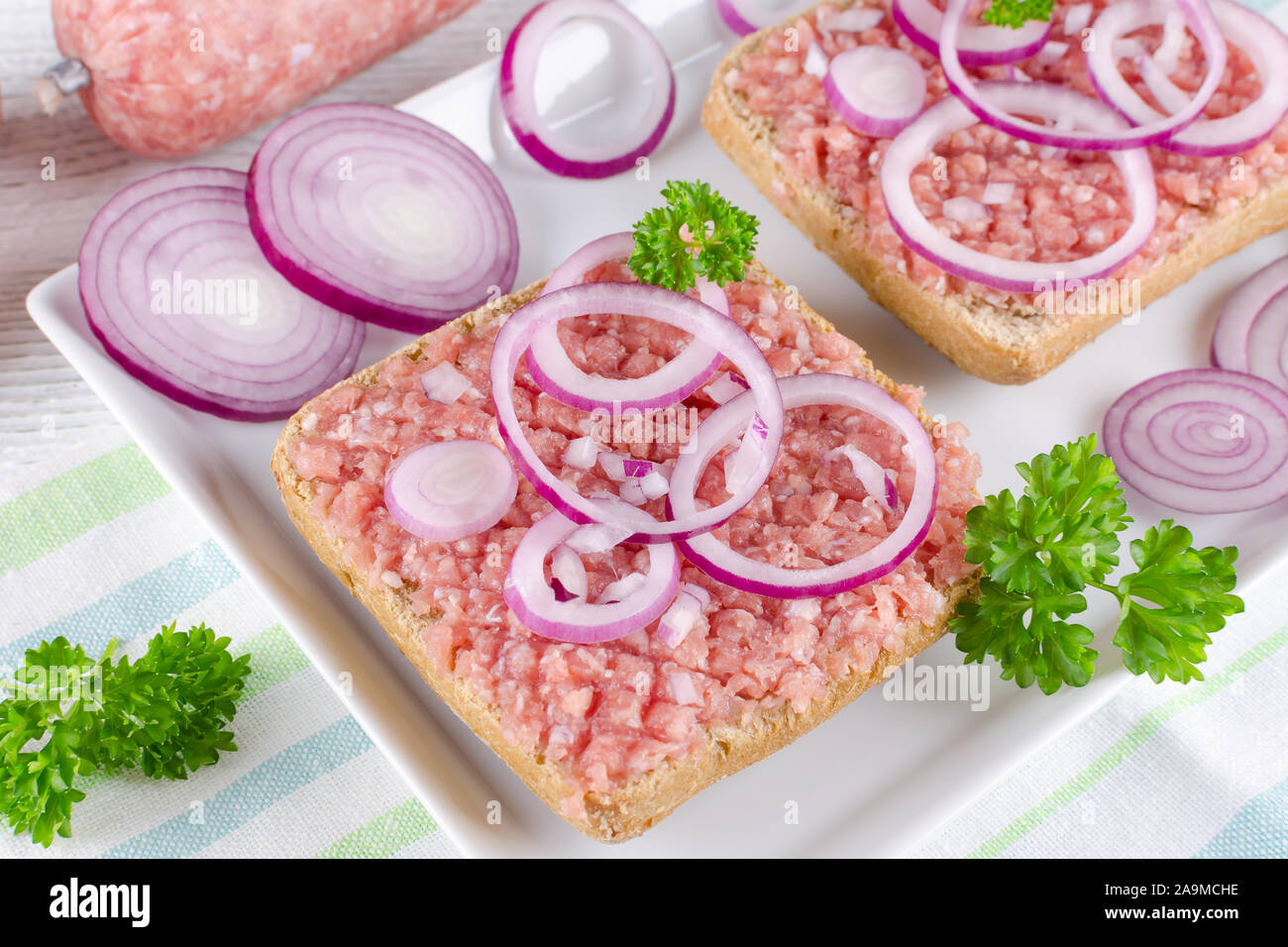 Sandwich tedesco mettbrotchen la carne macinata di maiale, bun e carne cruda con la cipolla e il prezzemolo, primo piano Foto Stock