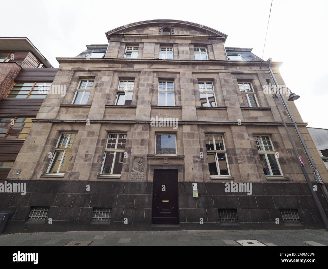 KOELN, Germania - circa agosto 2019: Wohnhaus Burgmauer 1 (costruito nel 1913) casa.Ave rosa generosa salve candens lilium significa grandine il nobile giglio bianco Foto Stock