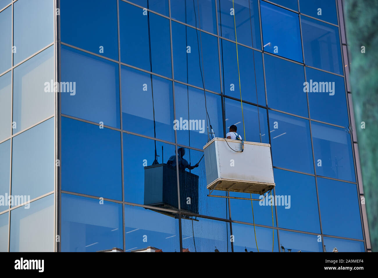 Lavoratore la pulizia di Windows in un moderno edificio di vetro, Pamplona Spagna Foto Stock