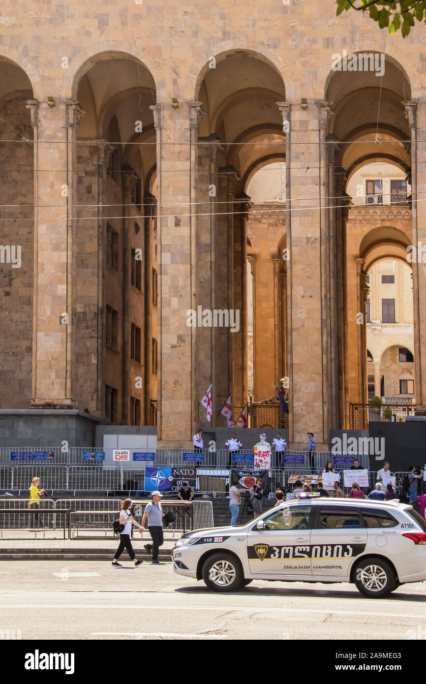 7-16-2019 a Tbilisi - Georgia protesta di fronte al parlamento con effige di Putin e pro-NATO di banner - recinzione di sicurezza e gli ufficiali di polizia e auto dr Foto Stock