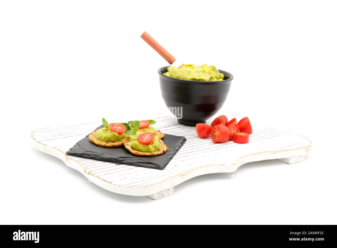 Cremosa di avocado spalmata sul grano intero crackers con pomodoro e basilico. Foto Stock