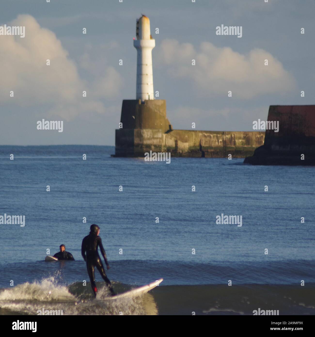 Surfisti in mare del Nord su un pomeriggio inverni, frangionde Beacon in background. Aberdeen, Scozia, Regno Unito. Foto Stock