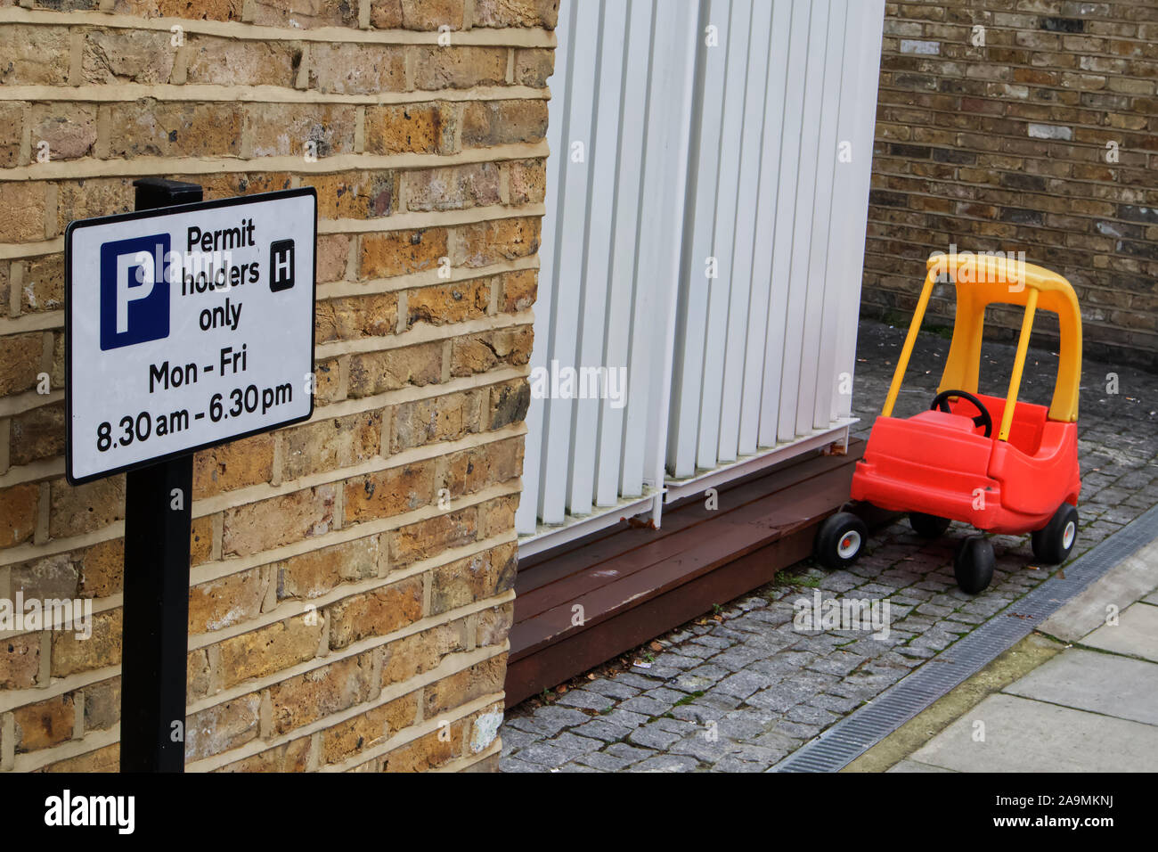 Supporto del permesso segno con un giocattolo macchina parcheggiata in una strada Foto Stock