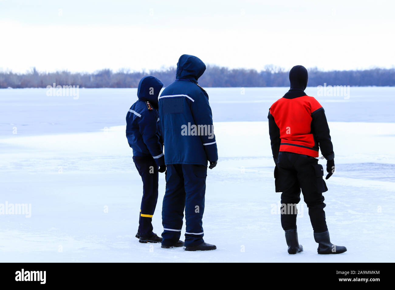 Soccorritori in uniforme e muta sono in servizio sul ghiaccio di un fiume congelato durante l'inverno la pesca e gli eventi sportivi. Salvataggio Foto Stock