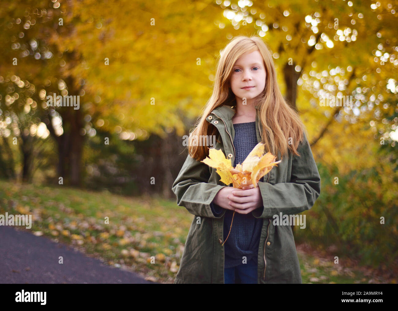 Bella dai Capelli rossi ragazza con foglie di autunno all'aperto Foto Stock