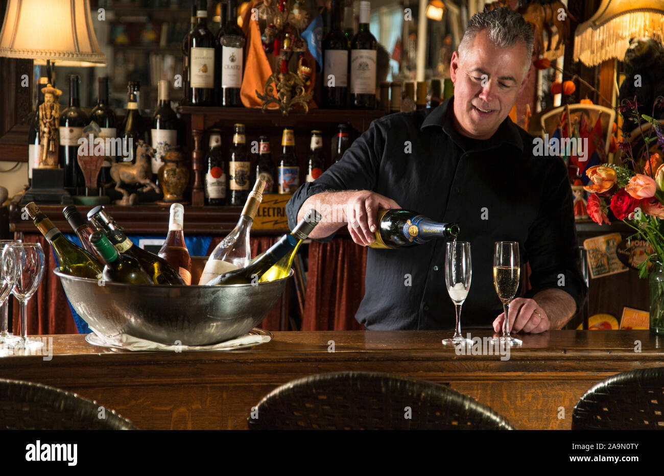 Barista versando wit le bottiglie di vino nel secchiello del ghiaccio nel Wine Bar, Pentagoet Inn, Maine, Stati Uniti d'America Foto Stock